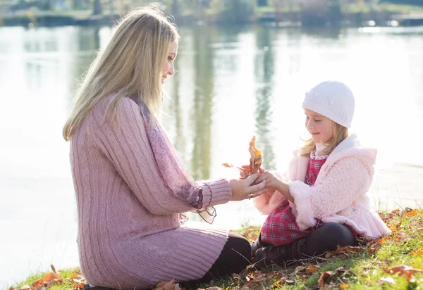 Menina com sua mãe no lago de outono — Fotografia de Stock