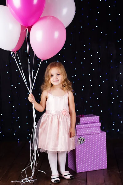 Little girl with pink balloons and gift boxes — Stock Photo, Image