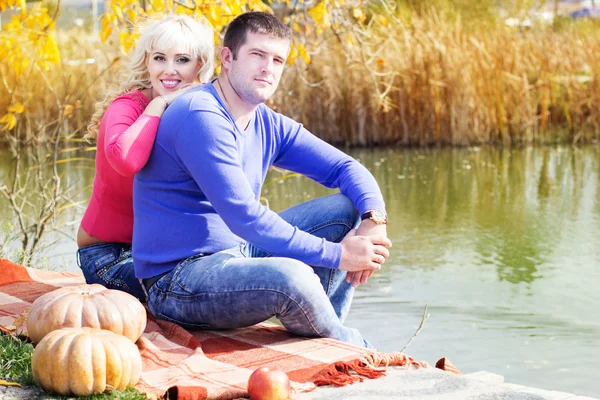 Молодая пара возле озера с тыквой, осеннее время — стоковое фото