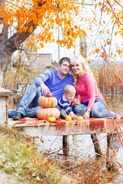 Young family near lake with pumpkins, autumn time — Stock Photo, Image