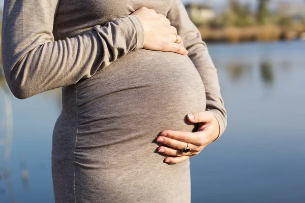 Buik van zwangere vrouw over de aard — Stockfoto