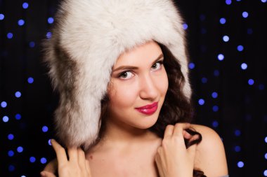 Tüylü kış şapkalı hoş gülümseyen kız