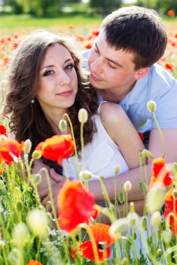 Poppies tam bir çayır üzerinde genç mutlu çift