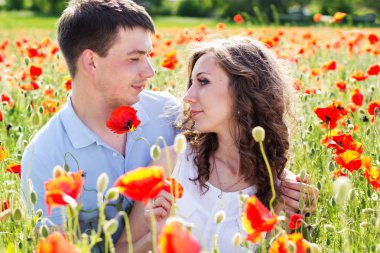 Poppies tam bir çayır üzerinde genç mutlu çift