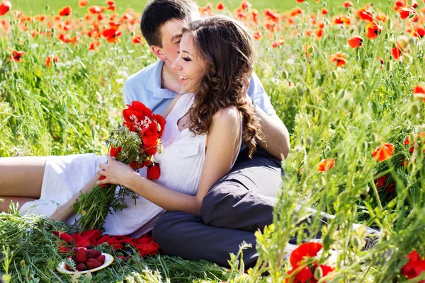 Poppies tam bir çayır üzerinde genç mutlu çift — Stok fotoğraf