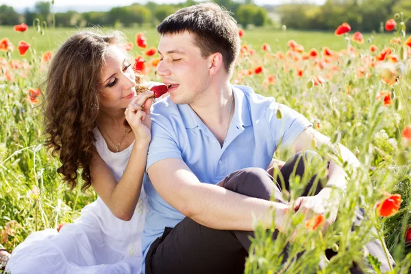 Jovem casal feliz em um prado cheio de papoilas — Fotografia de Stock