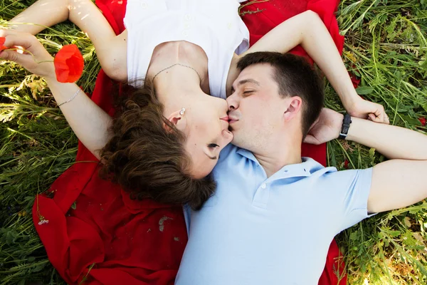 Junges glückliches Paar auf einer Wiese voller Mohn — Stockfoto