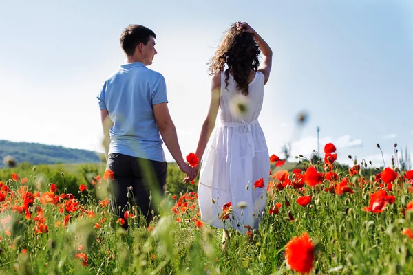 Young happy couple on a meadow full of poppies — Stock Photo, Image