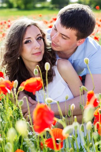 Junges glückliches Paar auf einer Wiese voller Mohn — Stockfoto