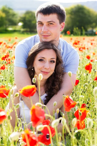 Jovem casal feliz em um prado cheio de papoilas — Fotografia de Stock