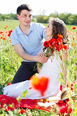 Poppies tam bir çayır üzerinde genç mutlu çift