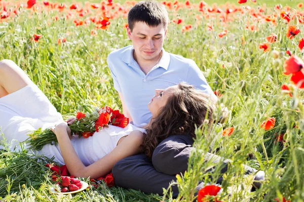 Poppies tam bir çayır üzerinde genç mutlu çift — Stok fotoğraf