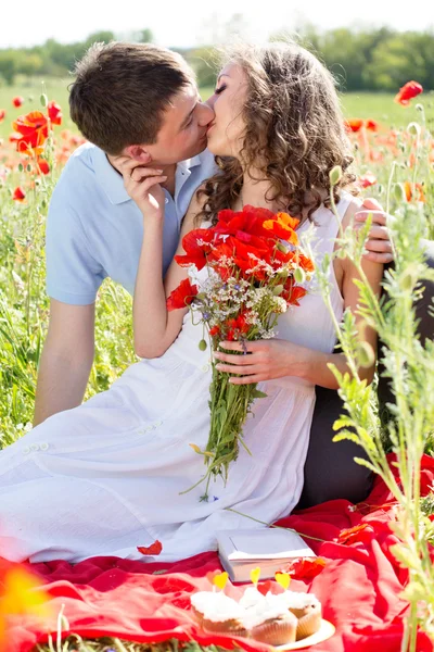 Jovem casal feliz em um prado cheio de papoilas — Fotografia de Stock