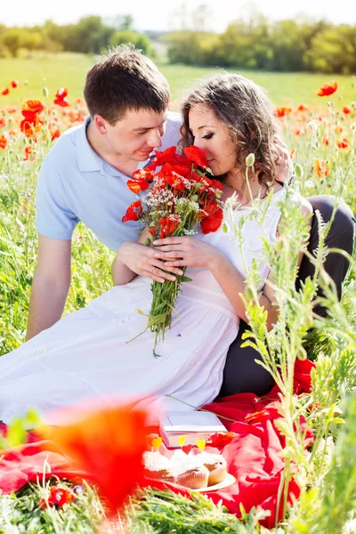 Jovem casal feliz em um prado cheio de papoilas — Fotografia de Stock
