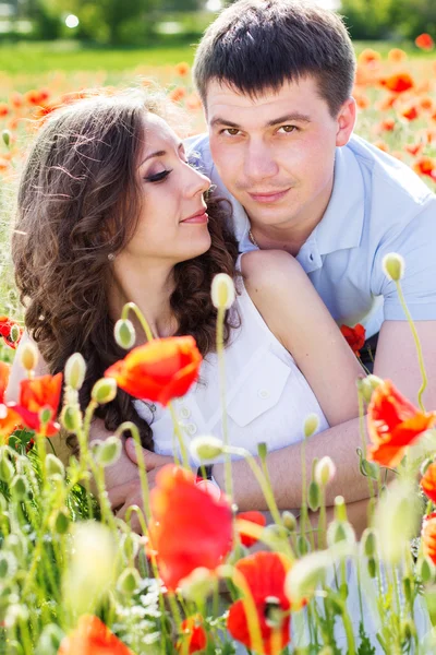 Poppies tam bir çayır üzerinde genç mutlu çift — Stok fotoğraf