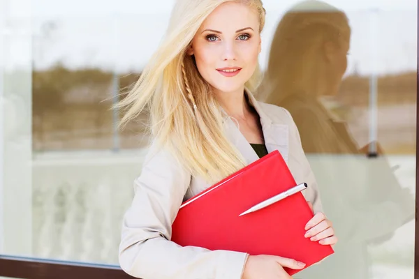 Joven chica gerente con una carpeta roja y libros — Foto de Stock