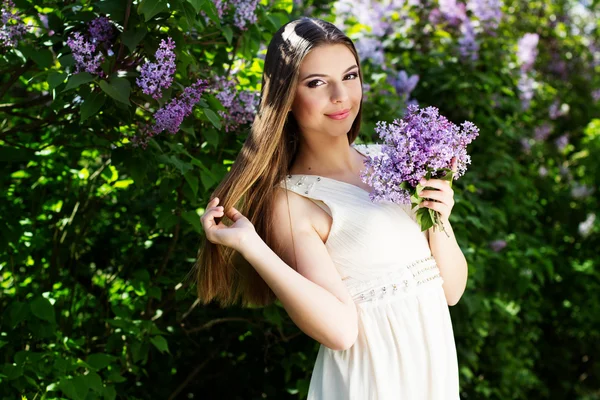 Schöne Mädchen mit einem Flieder Blumen — Stockfoto