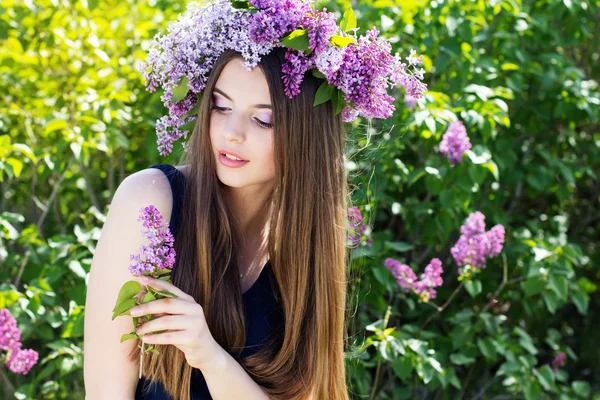 Mooi meisje met krans van lila bloemen — Stockfoto