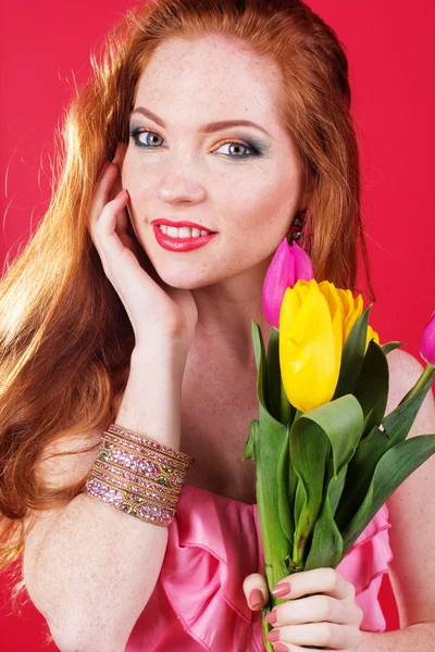 Beautiful redheaded girl is holding tulips — Stock Photo, Image