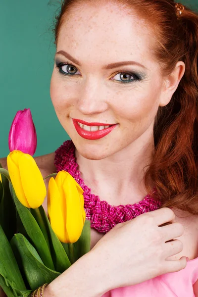 Schöne rothaarige Mädchen hält gelbe Tulpen — Stockfoto