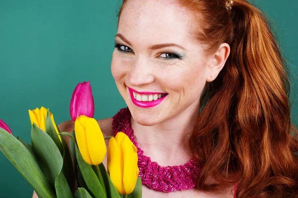 Beautiful redheaded girl is holding tulips — Stock Photo, Image