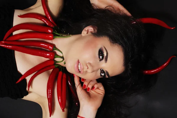 Chica morena diablo con pimientos rojos cayennes — Foto de Stock