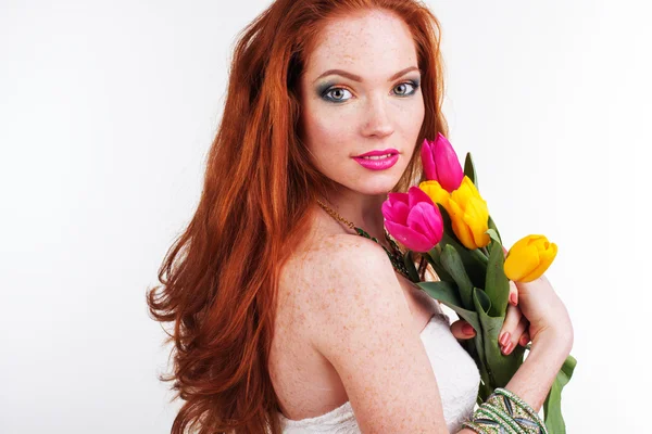 Beautiful redheaded girl is holding tulips — Stock Photo, Image