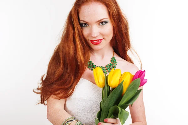 Redheaded girl with freckles is holding tulips — Stock Photo, Image