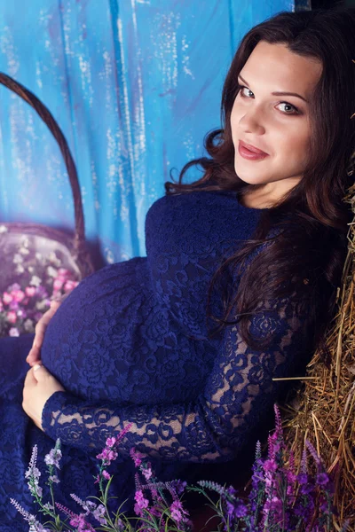 Pregnant pretty woman with flowers in studio — Stock Photo, Image