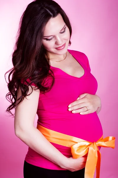 Studio portrait of pregnant woman holding her belly — Stock Photo, Image