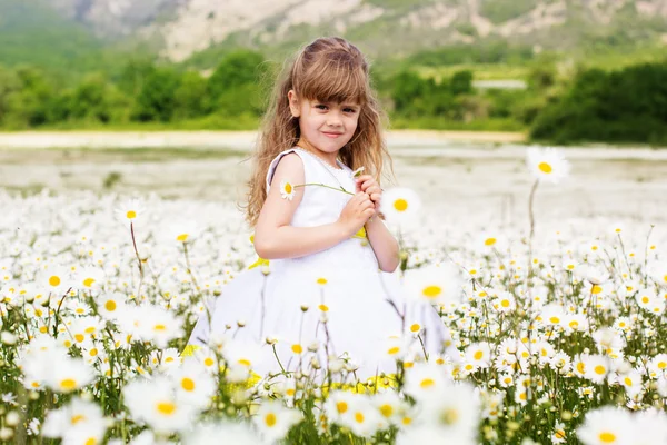 Lyckligt barn flicka på camomile field — Stockfoto