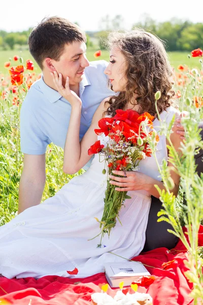 ポピーの草地に若いカップルします。 — ストック写真