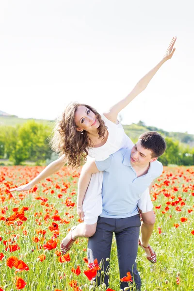 Mutlu kız ve oğlan bir çayır poppies tam üzerinde — Stok fotoğraf