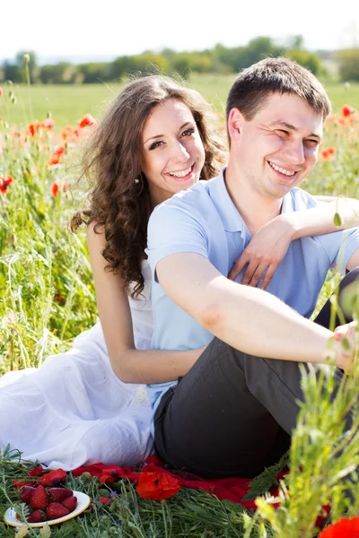 Chica feliz y niño en un prado lleno de amapolas — Foto de Stock