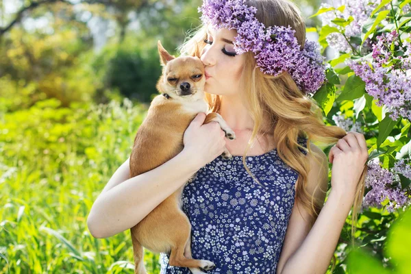 Beautiful girl with a wreath of lilac flowers and dog — Stock Photo, Image