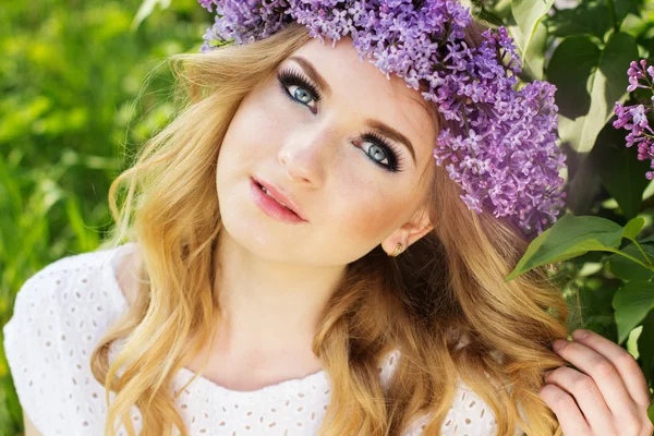 Teen blonde meisje met krans van lila bloemen — Stockfoto