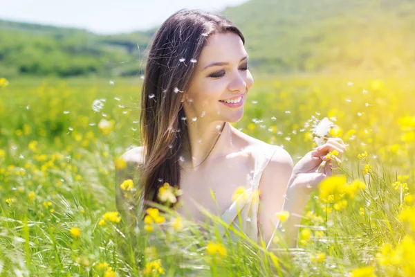 Krásná dívka s pampelišky ve žlutém poli — Stock fotografie