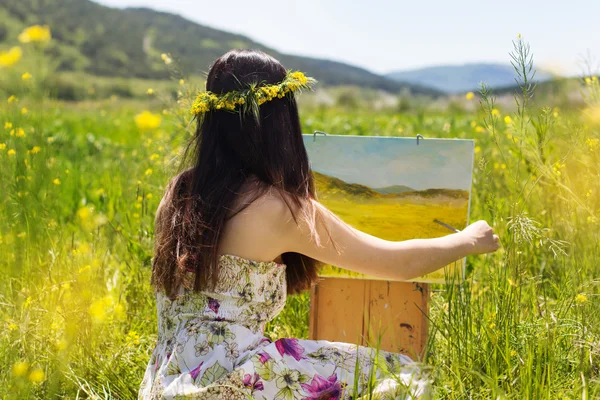 Pretty painter girl painting in yellow field — Stock Photo, Image