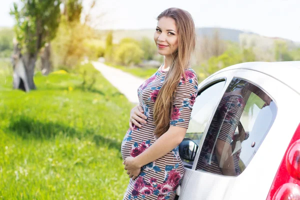 Happy těhotná žena stojící poblíž auto — Stock fotografie