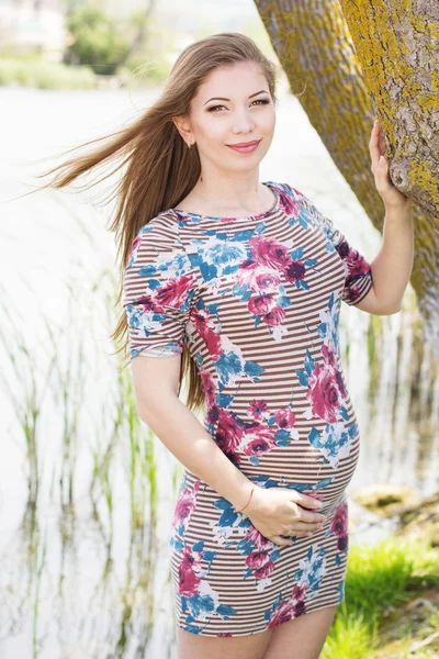 Беременная девушка стоит возле дерева — стоковое фото
