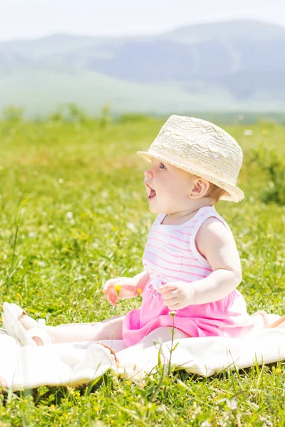 Joyeux bébé fille est assis sur l'herbe — Photo