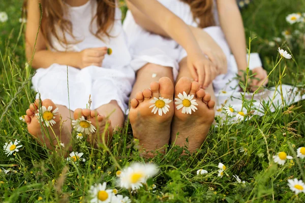 Deux paires de pieds d'enfants avec des fleurs de marguerite — Photo