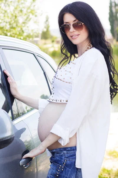 Zwangere mooi meisje is permanent in de buurt van auto — Stockfoto