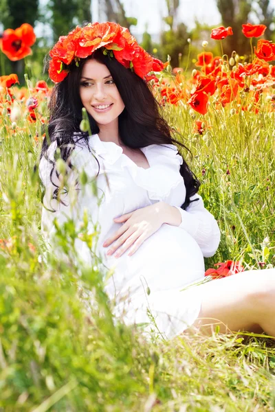 Happy pregnant girl on poppy field — Stock Photo, Image