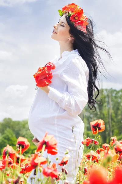 Счастливой беременной девушки на маковом поле — стоковое фото