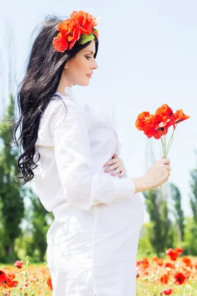 Hamile kız haşhaş sahada elbise giyiyor — Stok fotoğraf