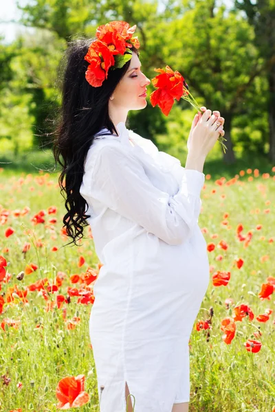 Pregnant girl is wearing dress on poppy field — Stock Photo, Image