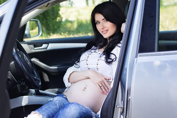 Zwangere mooi meisje zit in auto — Stockfoto