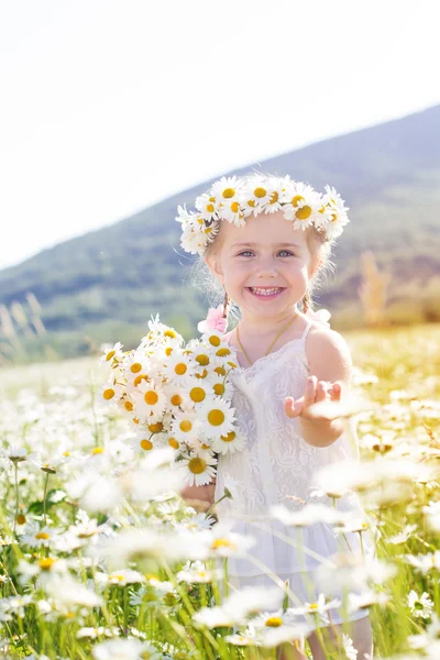 Smiling little girl with bouquet of chamomiles — Stock Photo, Image