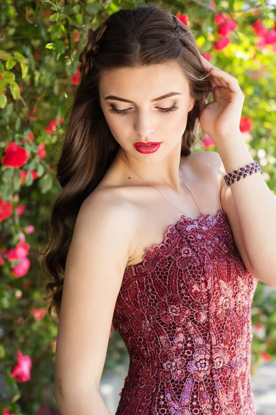 Belle jeune femme pose près des roses — Photo